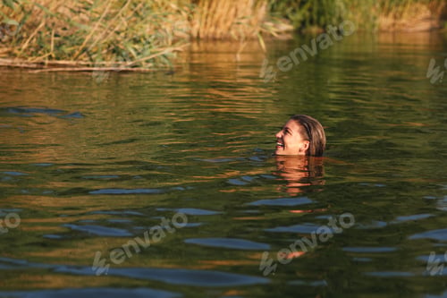 Preview: Young woman enjoys a summer day swimming in the river