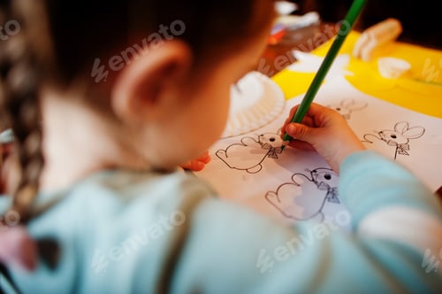 Preview: Preparing to Easter concept. Little girl drawing bunny.