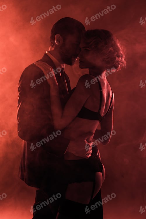 Preview: Wonderful couple hugging on red smoke background