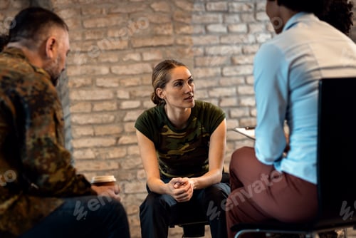 Preview: Female soldier talking with diverse group of veterans during PTSD support group.