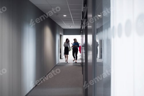 Preview: Colleagues in conversation walking down an office hallway.