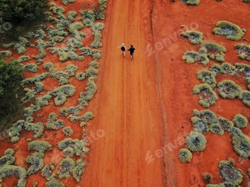Preview: High angel view of a young couple walking on an orange dirt road