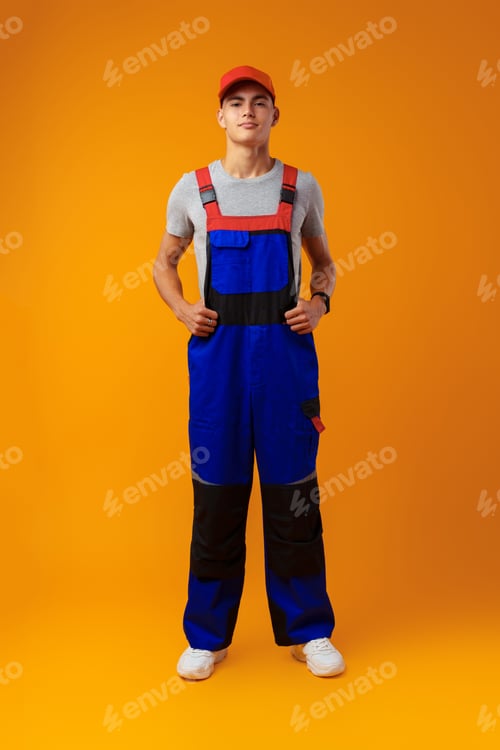 Preview: Full length shot of a young male worker in uniform on yellow background