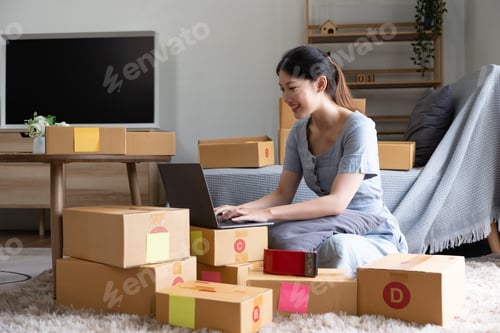 Preview: Start up small business, SME female owner checking order online to prepare to pack a box of goods