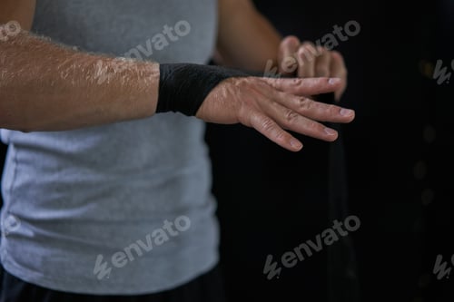 Preview: Anonymous kickboxer wrapping bandage on hand in gym