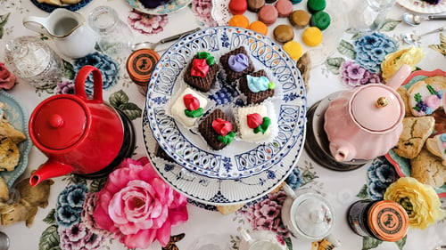 Preview: Dining room table set for tea party with delicious unhealthy food.