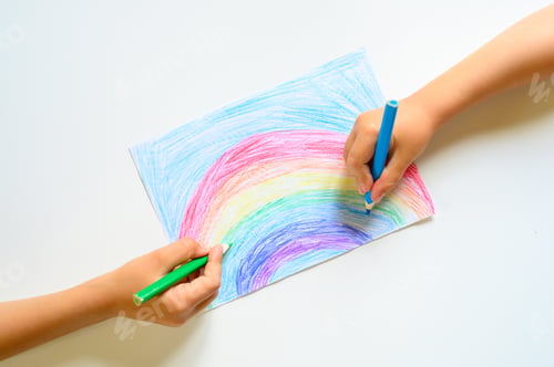 Preview: kid's hands together draw a rainbow colored pencils on white background