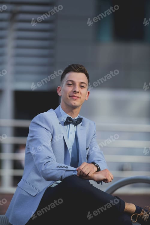 Preview: Vertical shot of a young attractive male in a formal suit posing outdoors