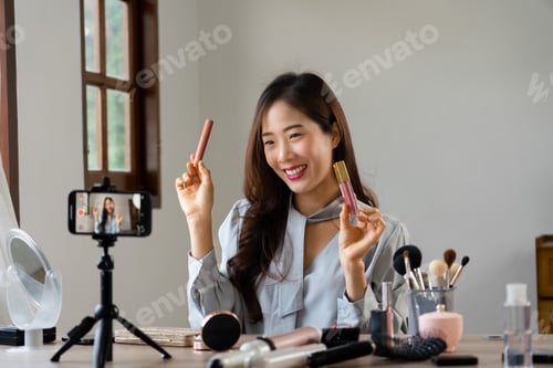 Preview: Beauty blogger holding lipstick and showing product to reviewing cosmetic in makeup vlogger