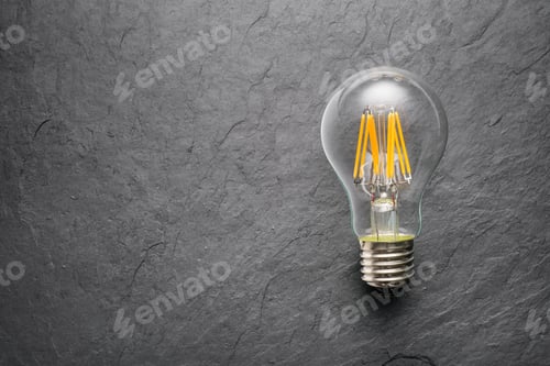Preview: Transparent LED filament light bulb on black background.
