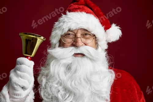 Preview: Close up of caucasian Santa Claus on red background and holding a golden bell