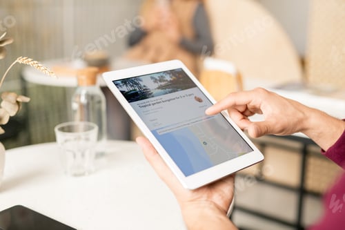 Vista previa: Un hombre entrega la pantalla de la tableta desplazándose por el sitio web de viajes