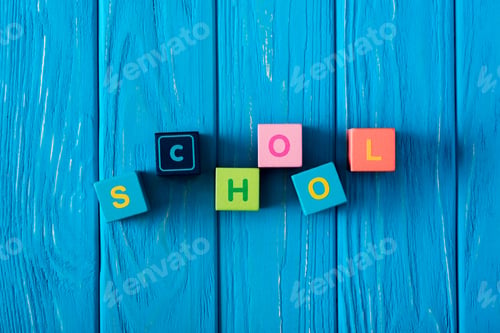 Preview: top view of lettering school made from cubes on blue wooden background