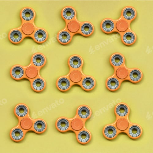Preview: Many orange fidget spinners lies on texture background of fashion pastel orange color paper
