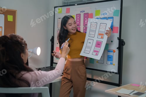Visualização: Duas web designers estão discutindo e analisando o wireframe de uma interface de aplicativo móvel