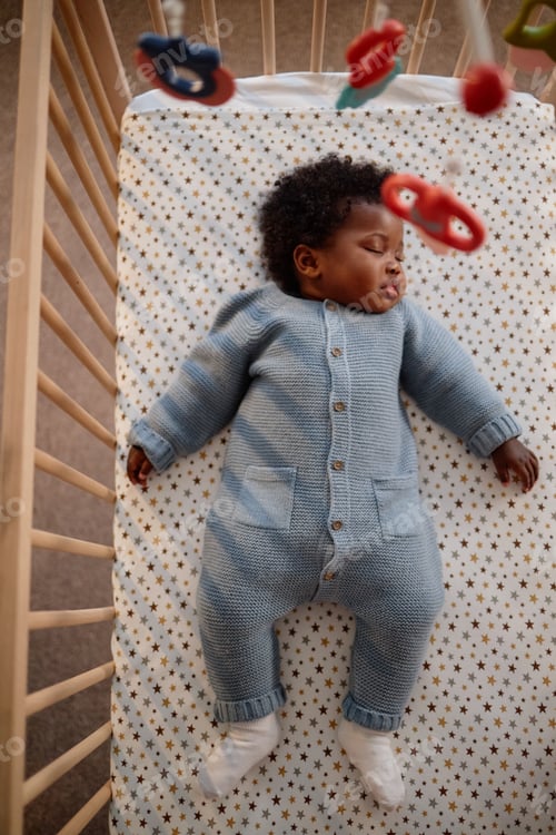 Preview: Black Baby Girl Dressed in Romper Sleeping in Crib Indoors