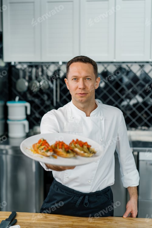 Preview: Professional satisfied chef showing freshly prepared toast with roasted avocado and tomatoes