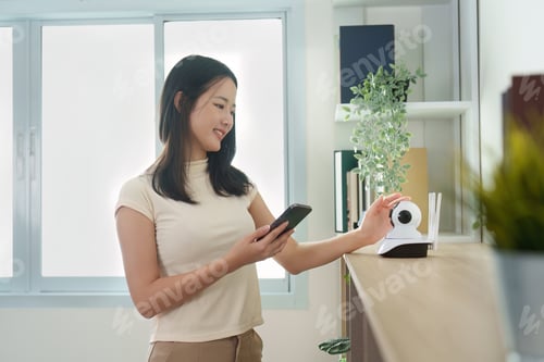 Preview: Smart Home: Woman managing security camera settings via smartphone