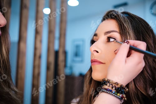 Preview: Professional makeup artist applying eyeliner on her client while doing her makeup in beauty salon.