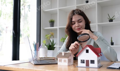 Preview: Happy woman hand holding magnifying glass and looking at house model, house selection, real estate