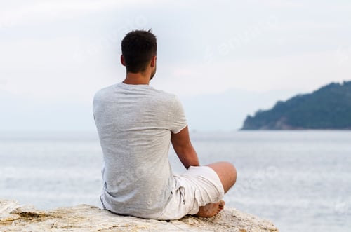 Preview: Young man sitting on the coast