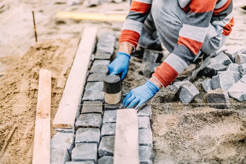 Preview: construction worker using industrial tools for stone pavement. granite blocks install details