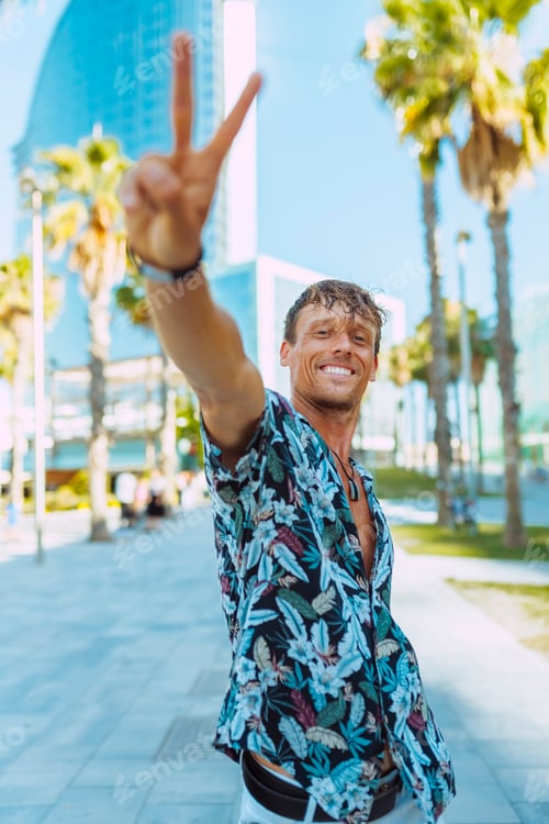 Preview: Attractive stylish man does peace victory sign at camera