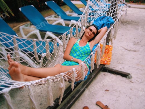 Preview: Woman in a bathing suit laying in a hammock relaxing on her tropical vacation