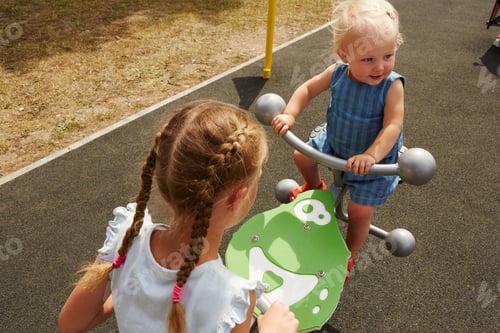 Preview: High angle view of sisters sitting on seesaw