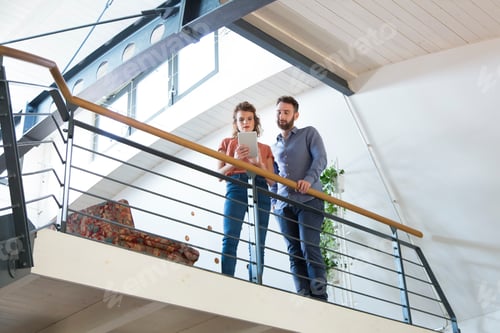 Aperçu: Colleagues standing on upper floor sharing tablet