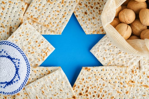 Preview: Passover celebration concept. Blue Star of David made from matzah, white and yellow roses, kippah an