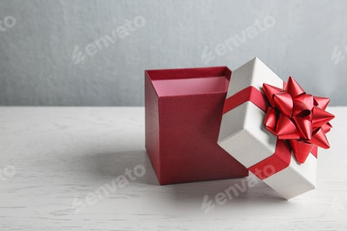 Vista previa: Beautiful gift box on white wooden table. Space for text