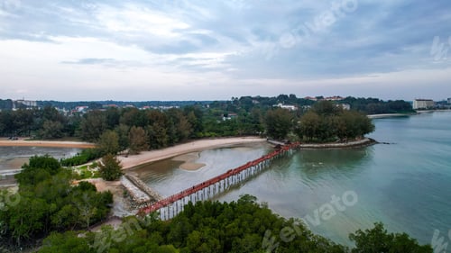 Preview: Scenic aerial view of a long, red bridge that spans the ocean, situated near a sandy beach