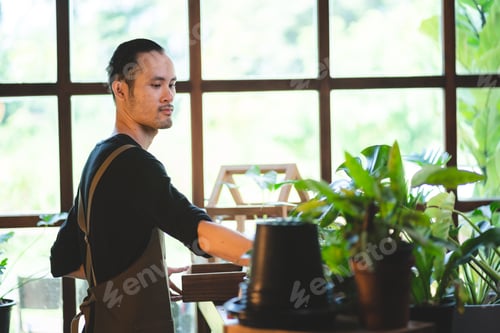 Preview: young Asian man are happy with growing plant in small green garden at home, hobby lifestyle