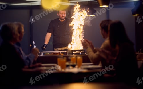 Preview: In a restaurant setting, a professional chef presents a sizzling steak cooked over an open flame