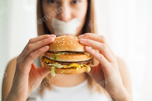 Preview: Young woman with duct tape over her mouth, preventing her to eat junk food