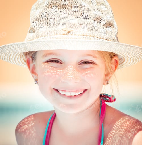 Preview: Smiling girl wearing a summer hat at beach