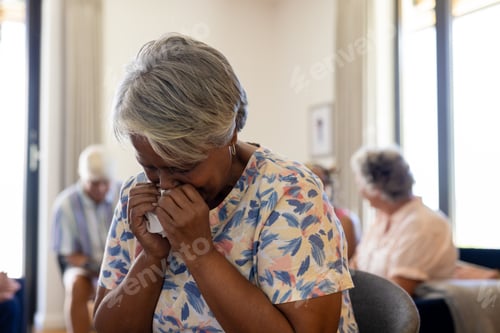 Preview: Distressed senior biracial woman holding tissue and crying in group therapy session