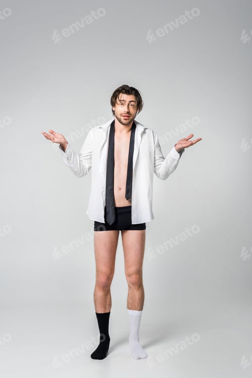 Preview: emotional man in shirt, underwear and black and white socks on grey backdrop