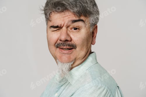 Preview: Senior grey man with mustache and beard winking at camera
