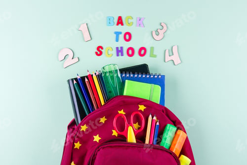 Preview: Back to school concept. Red backpack with different colorful stationery on pastel green background.