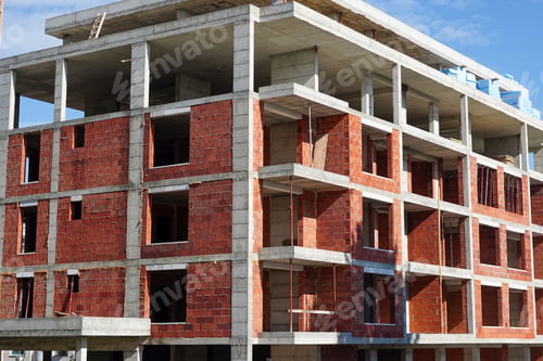 Preview: An unfinished brick and concrete building under construction against a blue sky
