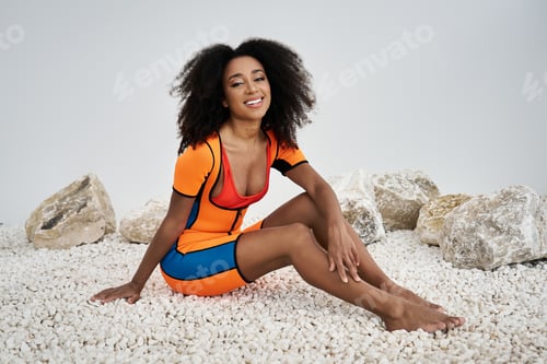 Preview: Stylish young woman radiates confidence in vibrant attire on a serene backdrop