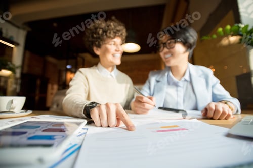 Preview: Two Businesswomen Collaborate Over Data Report in Cafe