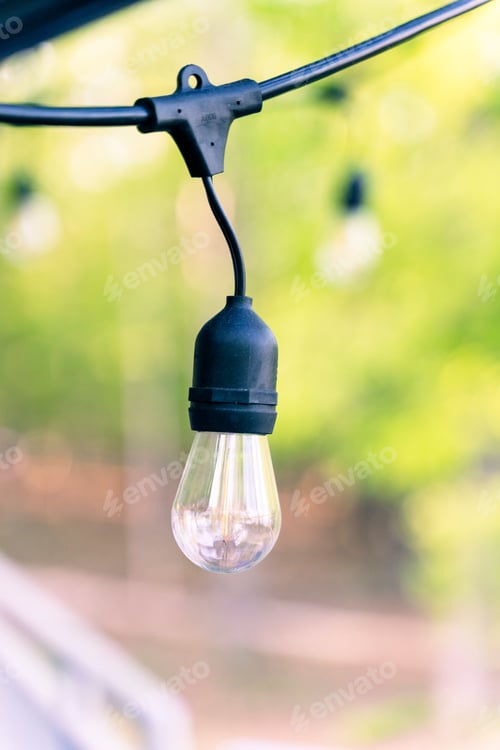 Preview: white hanging light bulb suspended from a wooden beam with a blurred background