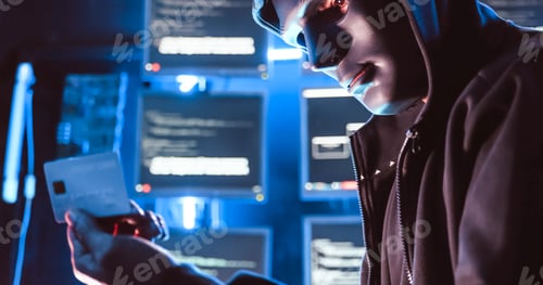 Preview: A hacker wearing a mask to cover his face is using computer to hack data to get ransom from victims.