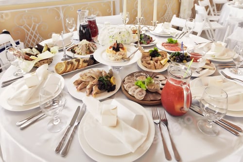 Preview: Banquet table with drinks, appetizers and salads on white tablecloth in a restaurant for guests