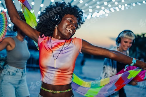 Preview: Happy friends dancing with headphones and colorful scarf at silent disco