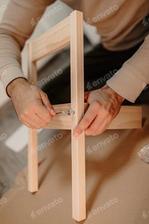 Preview: Skilled man assembles wooden furniture with a hex key