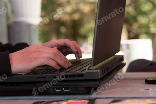 Preview: hands of man working at laptop in summer garden